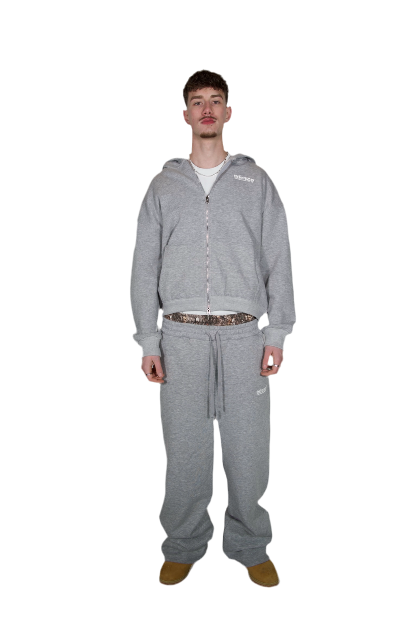 A man wearing a grey zipper hoodie and grey trousers