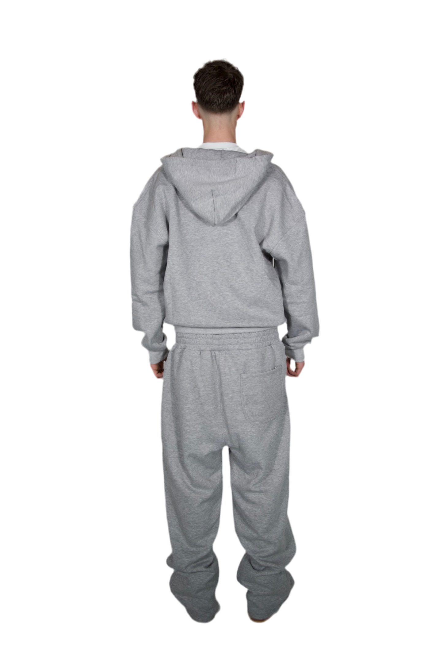 A man dressed in a grey hoodie and sweatpants, standing casually in a relaxed pose.