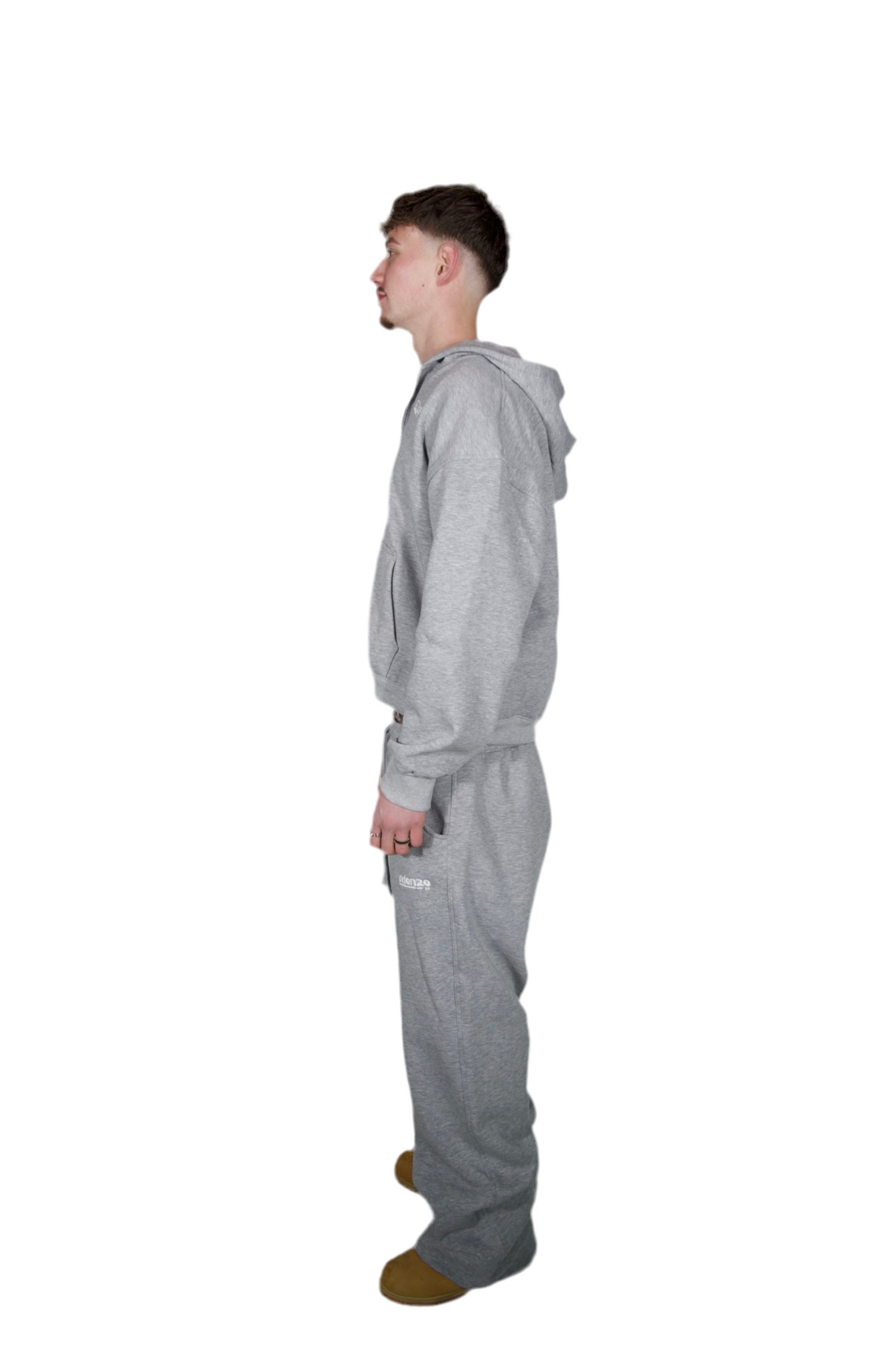 A man dressed in a grey hoodie and sweatpants, standing casually in a relaxed pose.