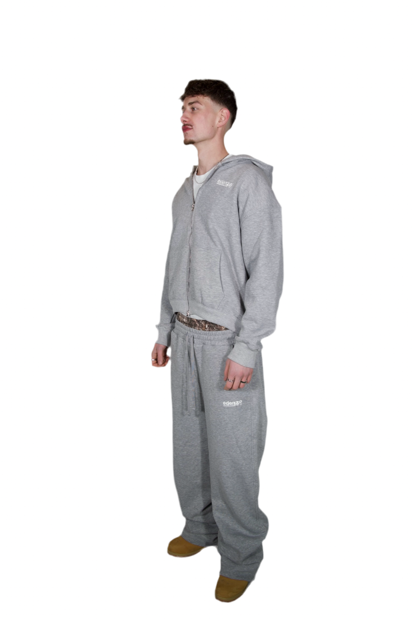 A man dressed in a grey hoodie and sweatpants, standing casually in a relaxed pose.