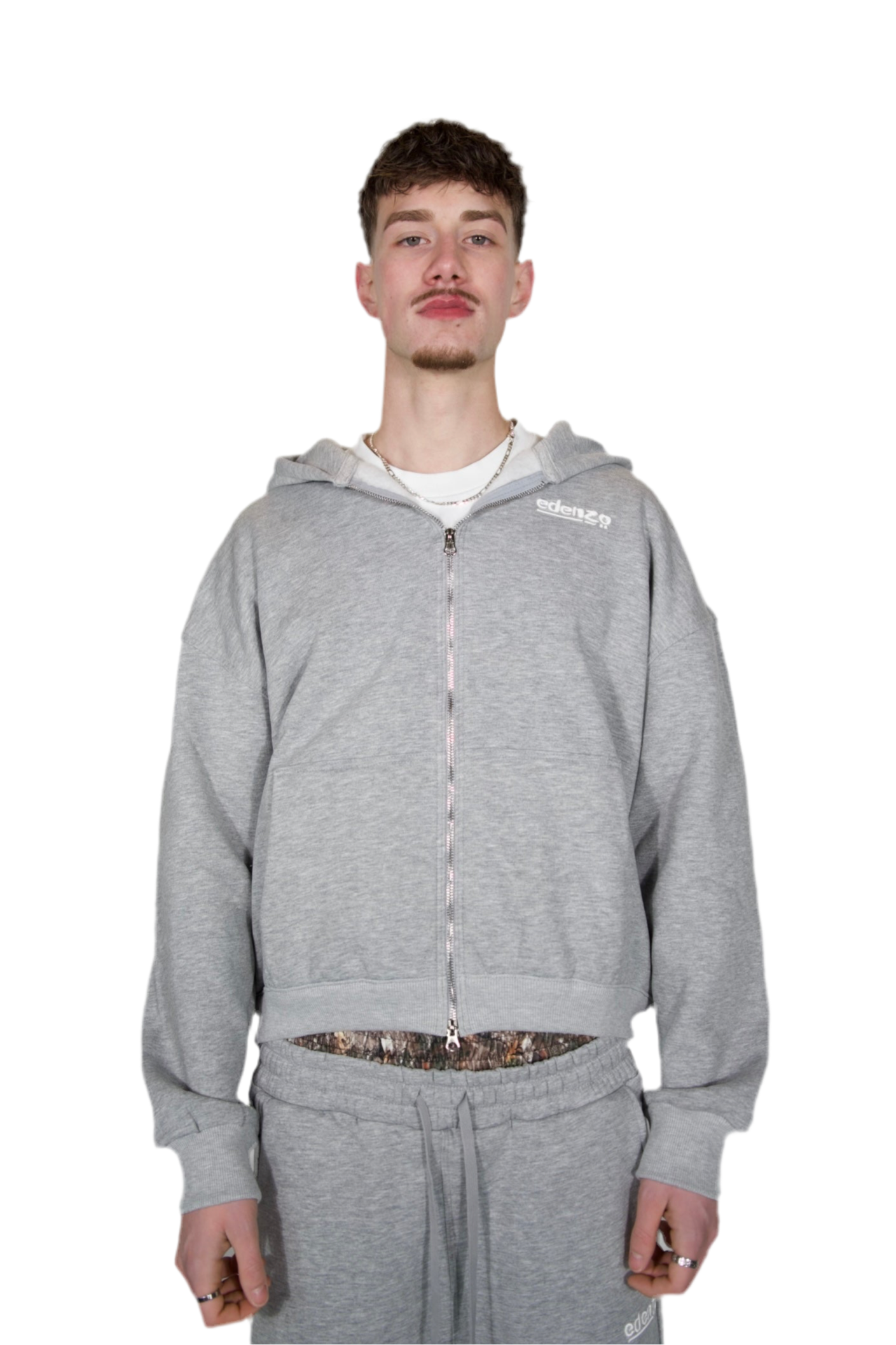 A man dressed in a grey hoodie and sweatpants, standing casually in a relaxed pose.