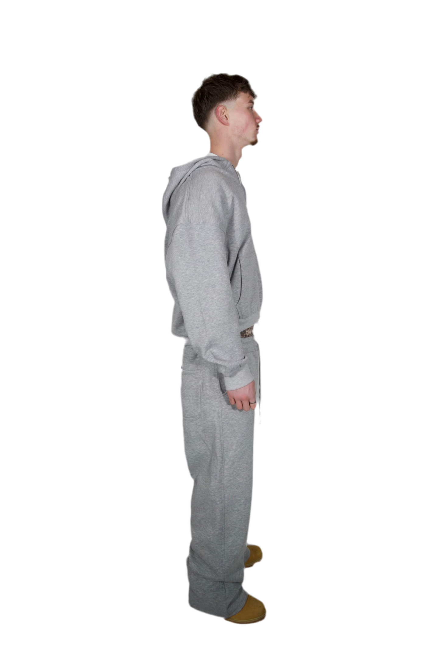 A man dressed in a grey hoodie and sweatpants, standing casually in a relaxed pose.
