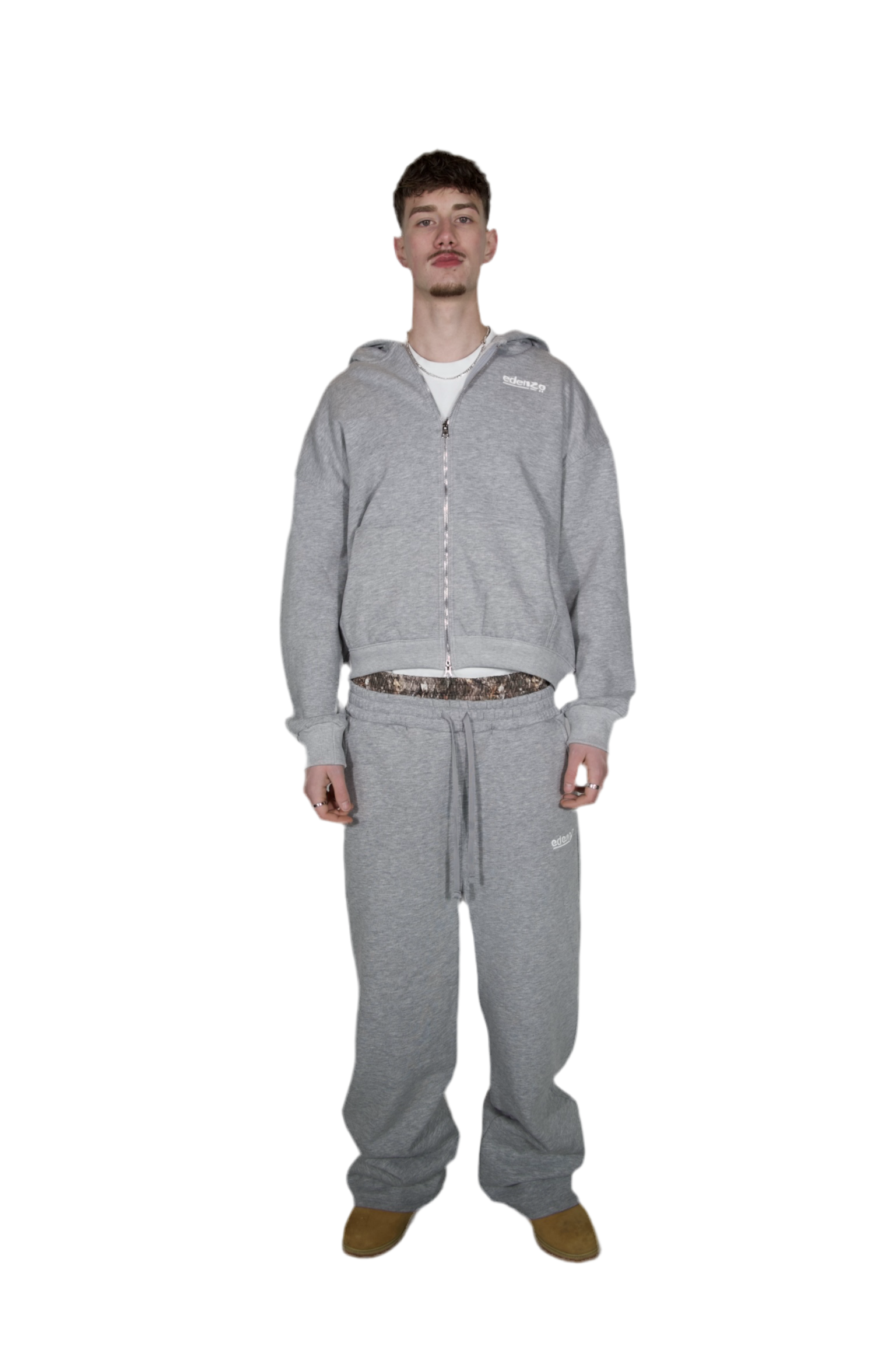 A man wearing a grey zipper hoodie and grey trousers
