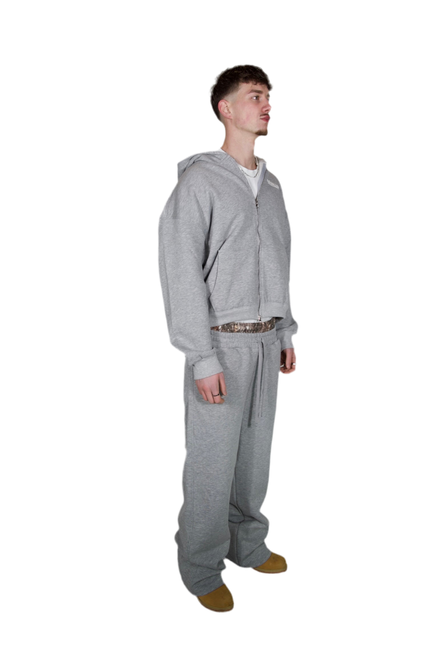 A man dressed in a grey hoodie and sweatpants, standing casually in a relaxed pose.