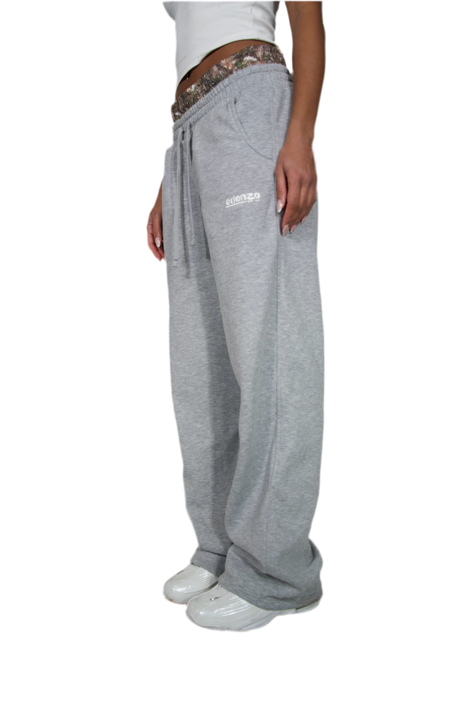 A woman dressed in grey sweatpants and white sneakers showcasing a casual and comfortable style.